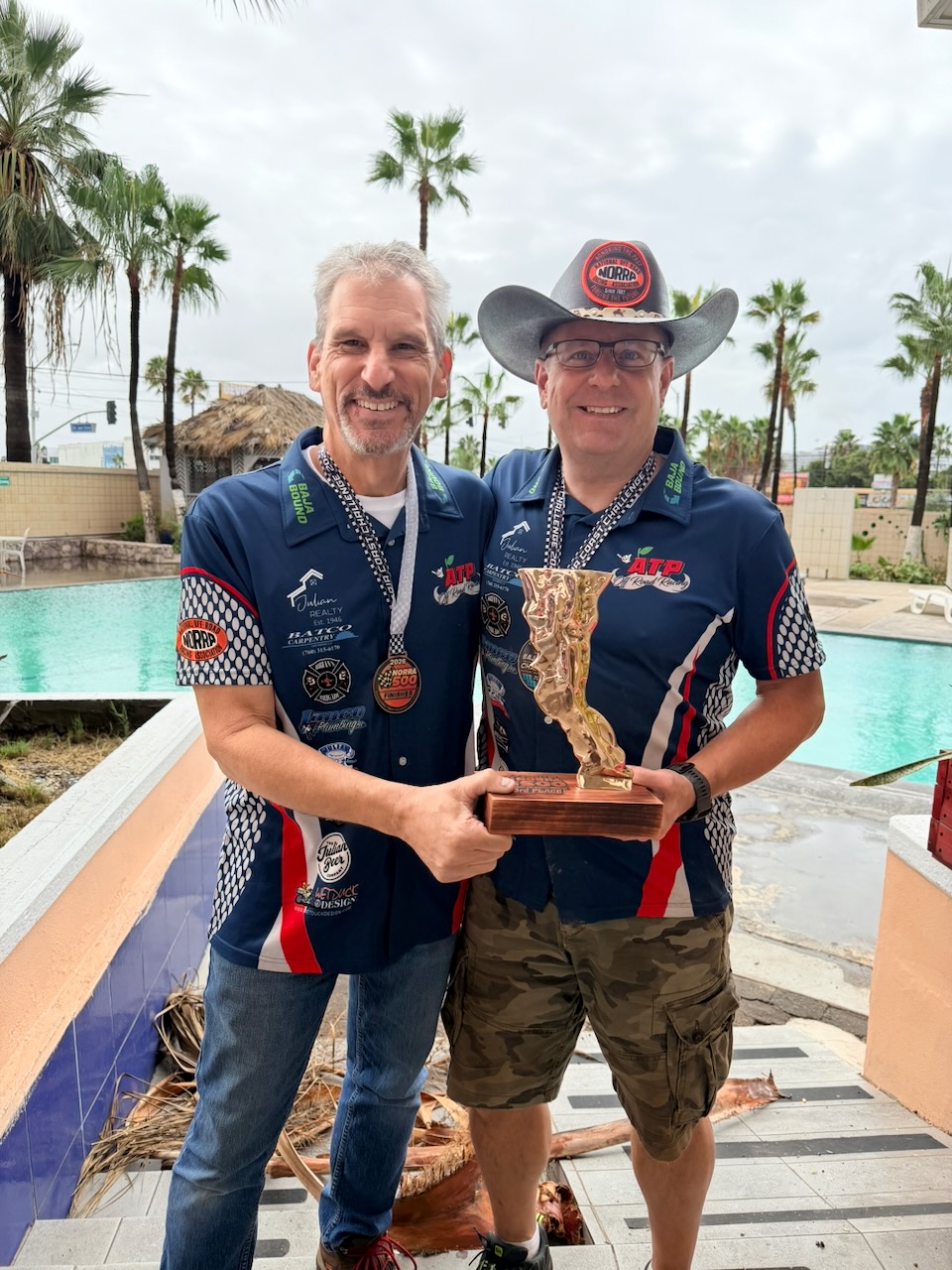 Mike and Josh holding the 2026 NORRA 500 third-place trophy